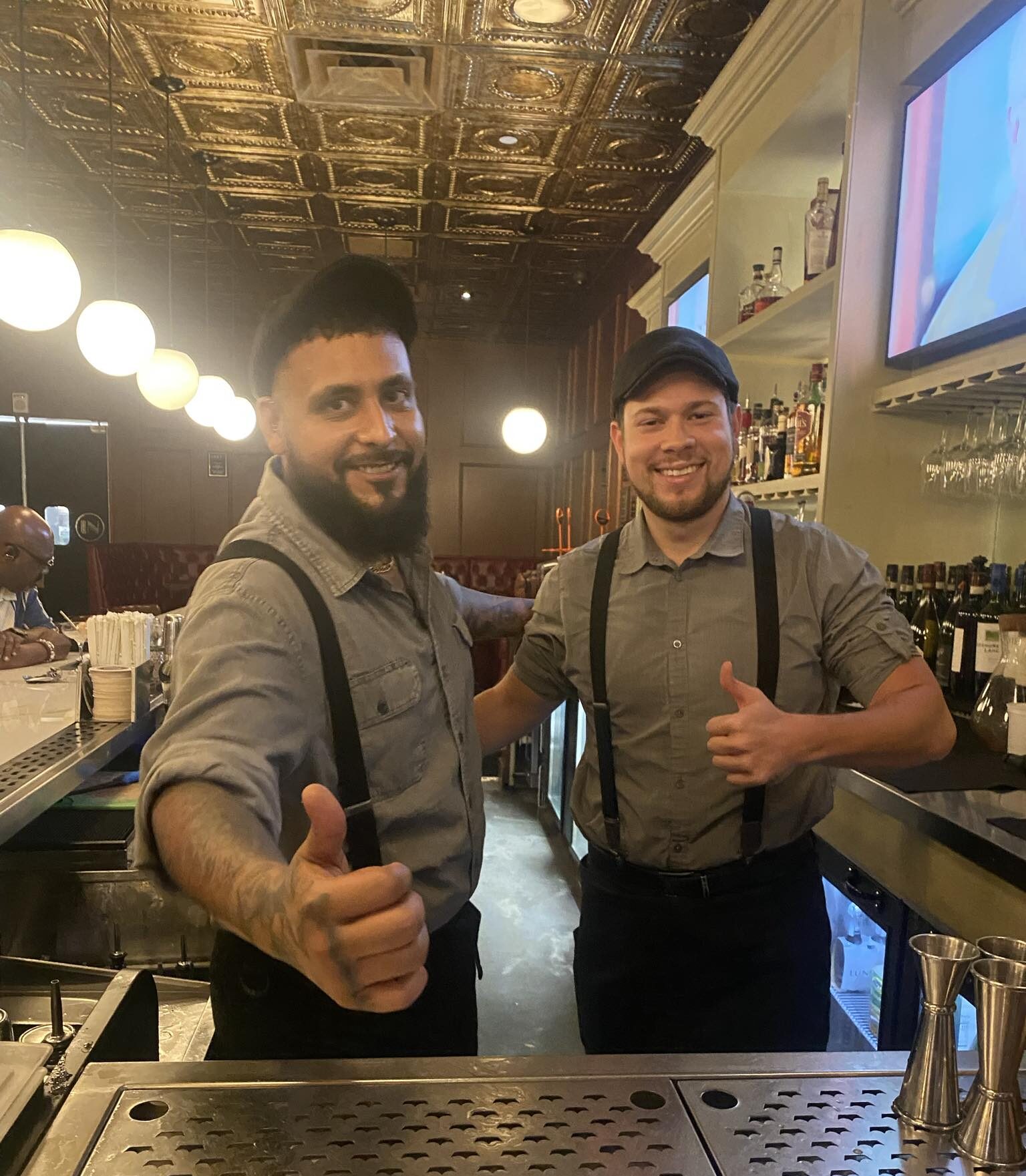 "AJ y Sam, camareros de Divieto en Aventura, Florida, mostrando sus habilidades mientras crean cócteles en un vibrante entorno de bar".