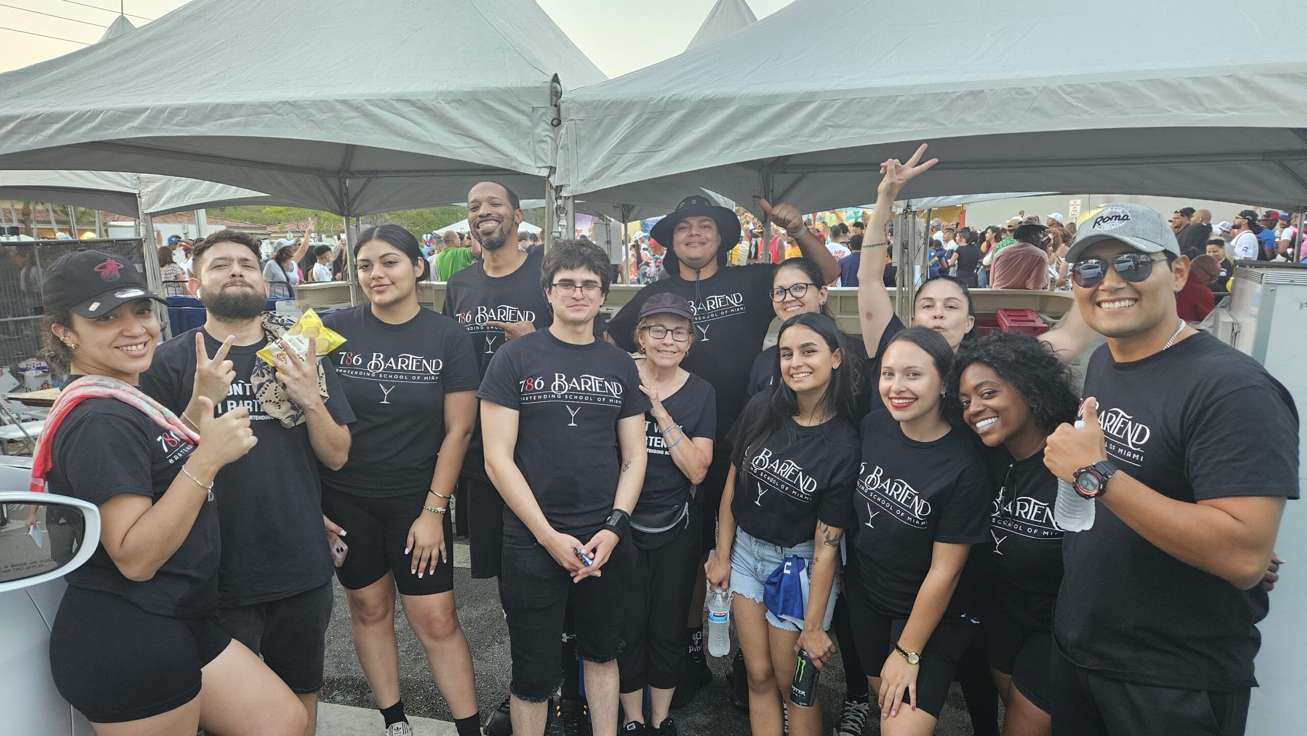 Estudiantes de 786-Bartend posando en el festival Calle Ocho 2025 en la Pequeña Habana después de trabajar en carpas de cerveza