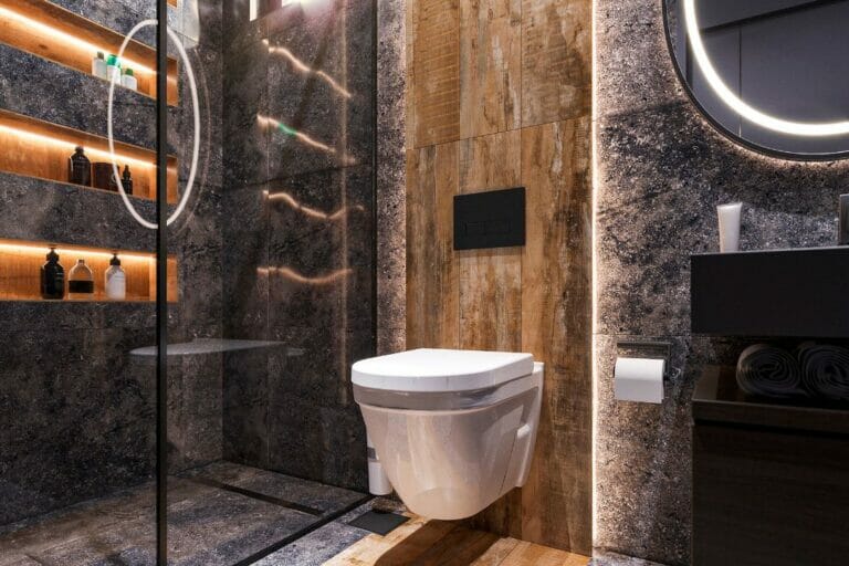 Moderne Küche und Badezimmer mit hängender Toilette, Holz- und Steinakzenten, Duschkabine aus Glas und beleuchteten Regalen mit Pflegeprodukten.