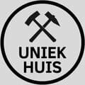 Schwarz-weißes rundes Logo mit gekreuztem Hammer und Hammersymbolen über "UNIQUE HOUSE" auf grauem Hintergrund, Symbol für Exzellenz im Design.