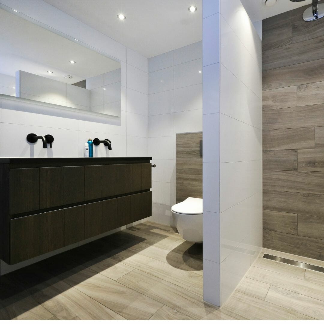 Badezimmer mit schwarzen Armaturen, Holzakzente, modernes Badezimmer, Holzakzente, schlankes Design, weiße Fliesen, dunkle Schränke, minimalistischer Stil, eingebauter Spiegel, stilvolle Sanitärkeramik, neutrale Farben, Wohnkomfort