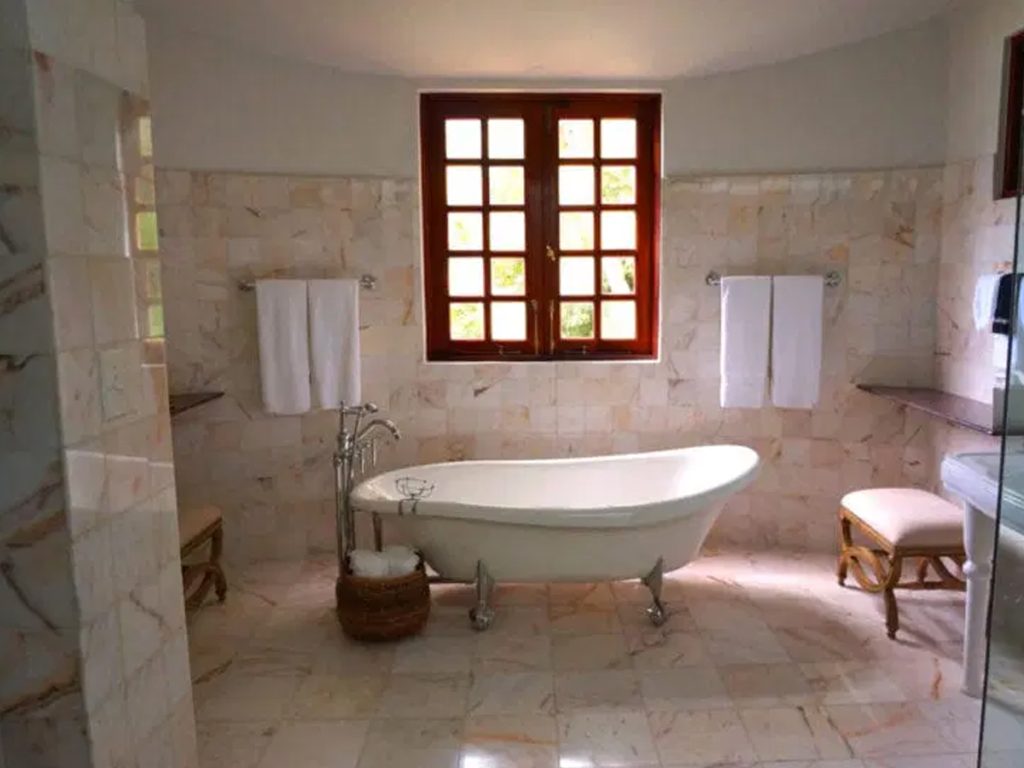 Dieses wunderschön renovierte Badezimmer verfügt über eine klassische Badewanne mit Klauenfüßen, zwei ordentlich aufgehängte Handtücher auf Gestellen, einen charmanten Weidenkorb und ein großes Fenster mit eleganten Holzrahmen.