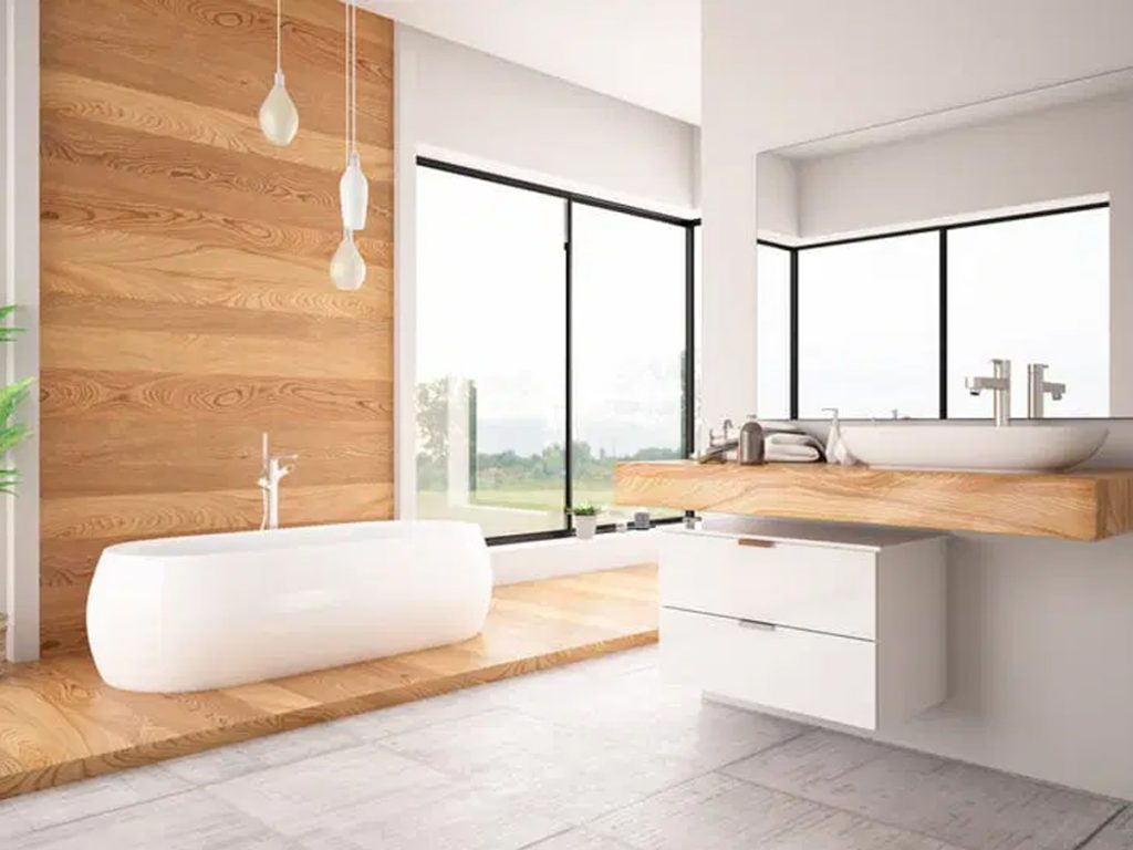 Modernes Badezimmer mit freistehender weißer Badewanne, Holzakzenten, einer Arbeitsplatte mit Waschbecken und großen Fenstern mit malerischem Blick nach draußen.