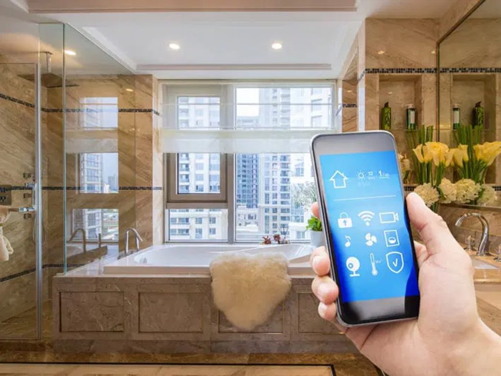 Eine Hand hält ein Smartphone mit einer Smart-Home-App-Schnittstelle vor dem Hintergrund eines luxuriösen Badezimmers. Das Ambiente umfasst ein modernes Badezimmer mit Badewanne, großem Fenster und dekorativen Pflanzen.