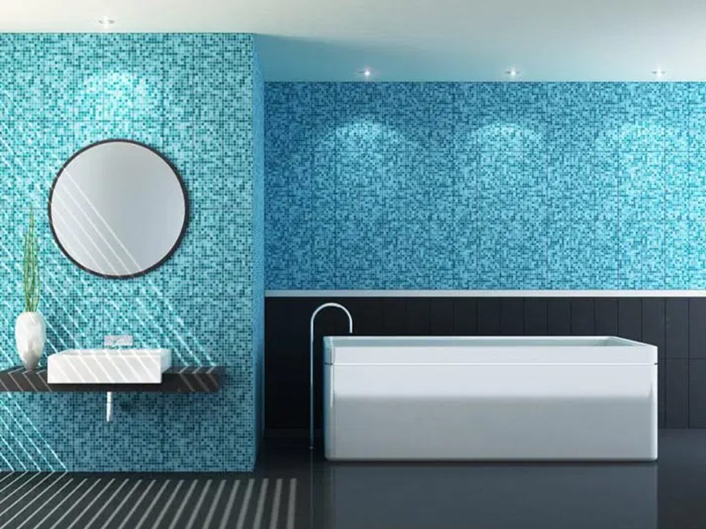Modernes Badezimmer mit blauen Mosaikfliesen, einem runden Spiegel, einem wandhängenden Waschbecken mit Vase und einer weißen Badewanne.