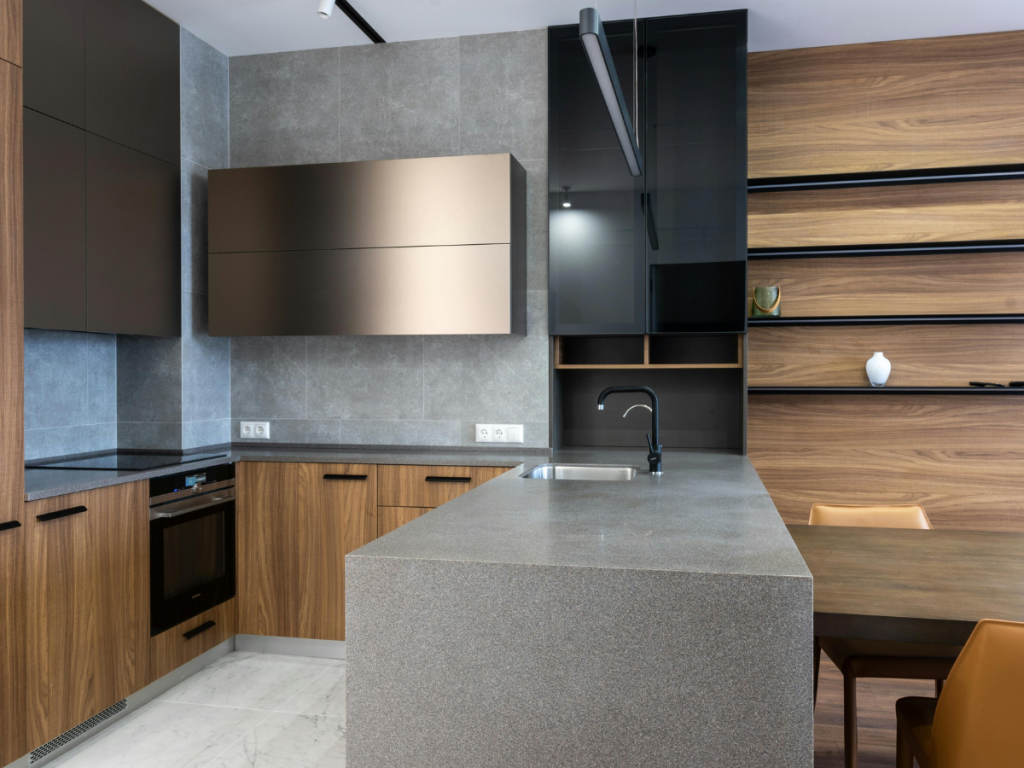Moderne Küche mit Holzschränken, einer grauen Insel und Einbaugeräten. Offene Regale an der rechten Wand haben ein minimalistisches Dekor, das an ein ruhiges Badezimmer erinnert. Der Raum wird durch einen weißen Marmorboden und eine elegante Deckenbeleuchtung aufgewertet.