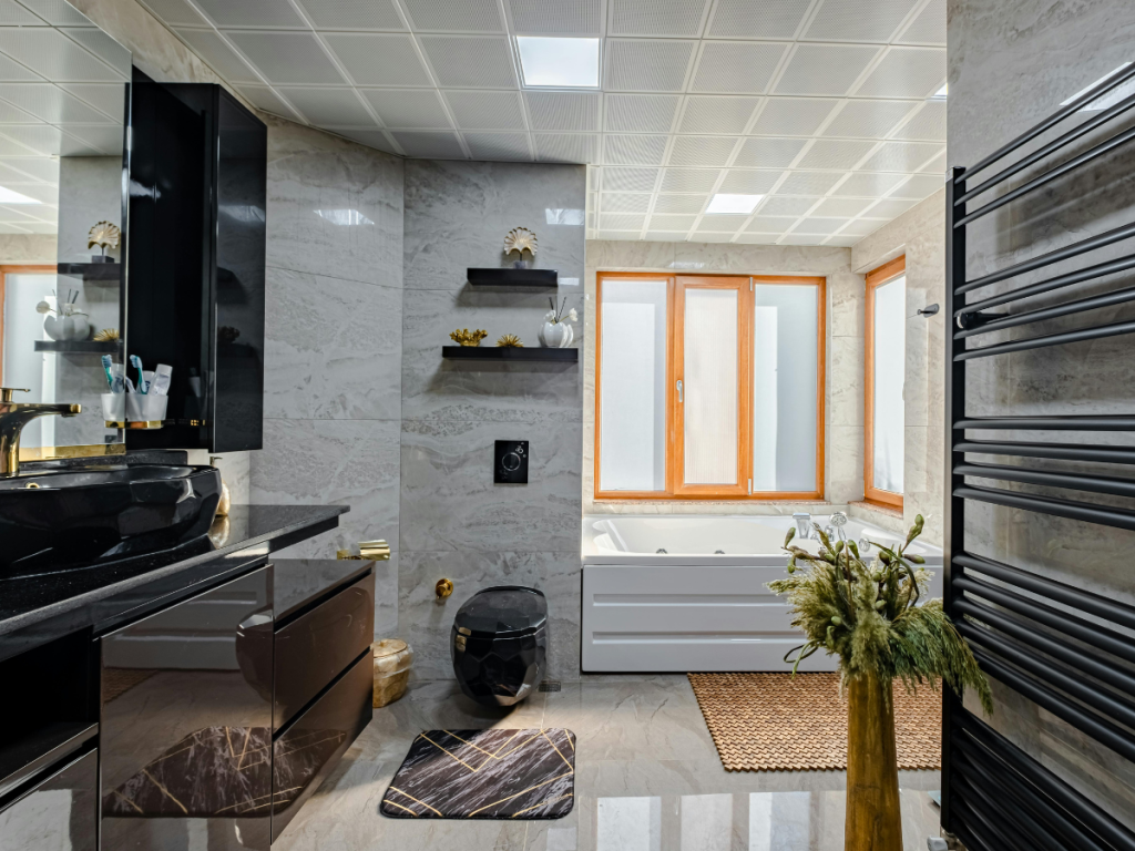 Modernes Badezimmerdesign mit Marmorwänden, schwarzen Armaturen und einer großen Badewanne. Dieser elegante Raum verfügt über holzveredelte matte Fenster, einen schlanken Wandspiegel, einen Handtuchwärmer und dekorative Pflanzen für einen Hauch natürlicher Ruhe.