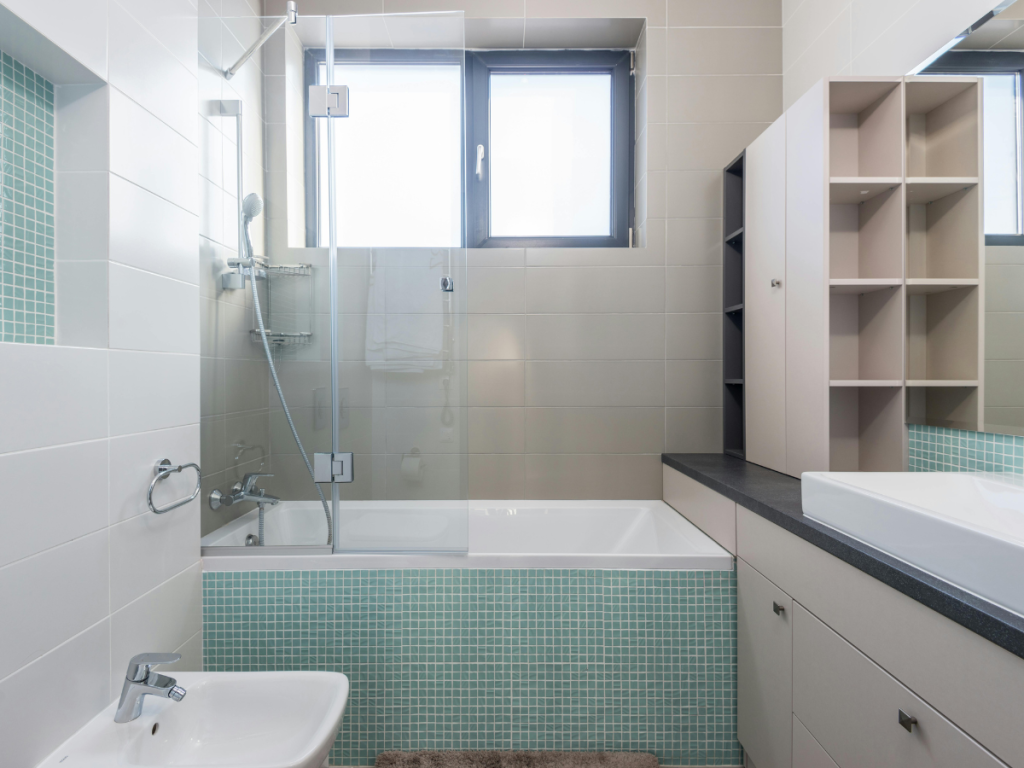Modernes Badezimmer mit Badewanne, Duschkabine aus Glas, Waschbecken und Regalen. Die Wände sind in Beige und Türkis gefliest. Ein Fenster sorgt für natürliches Licht über der Badewanne, das durch ein gut organisiertes Sanitärdiagramm wunderbar ergänzt wird, um eine effiziente Sanitärinstallation im gesamten Raum zu gewährleisten.