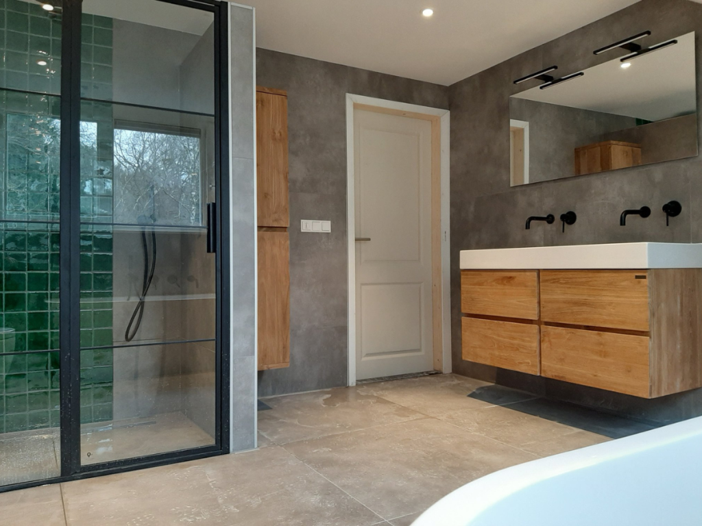 Modernes Badezimmer mit begehbarer Dusche mit grünen Fliesen, einem Holzwaschbecken mit Doppelwaschbecken und einem großen Spiegel. Das Innendesign zeigt eine schlanke weiße Tür, die das zeitgenössische Design perfekt ergänzt.