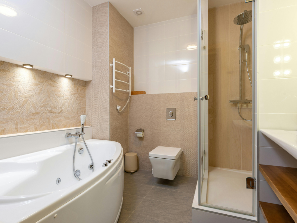 Modernes Badezimmer mit Eckbadewanne, wandhängendem Kleiderschrank, beheiztem Handtuchhalter, Duschkabine mit Glastür und beigen gefliesten Wänden, die die ruhige Farbpalette ergänzen.