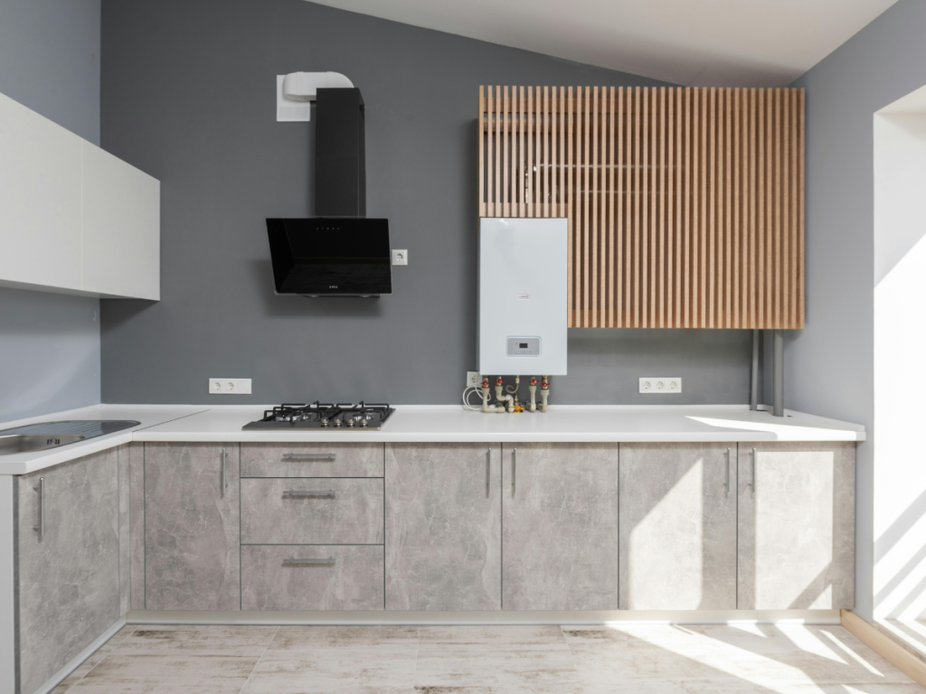 Moderne Küche mit grauen Schränken, weißer Arbeitsplatte, Gasherd, schwarzer Dunstabzugshaube, weißem Heizkessel und Verkleidung mit Holzlatten: perfekt für die Küche beim Kochen.