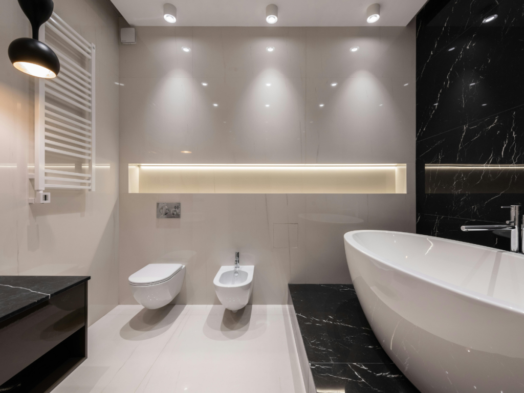 Modernes Badezimmer mit Wandschrank, Bidet, freistehender Badewanne, schwarz-weißen Fliesen und Einbaubeleuchtung.