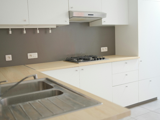 Moderne Küche, perfekt für kleine Küchen, mit Arbeitsplatten aus hellem Holz, weißen Schränken, einem eingebauten Gasherd, einer Spüle aus Edelstahl und einer eleganten grauen Rückwand.