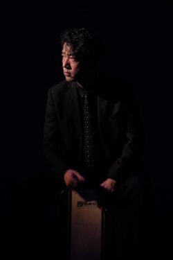 He discovered folk percussion instruments and began his career in music. Studied under Takeshi Nakamura. He has participated in orchestras of rock, pop, salsa, African, and Brazilian music, released a major album by his band (Shango Come Down Above Me) in 2005, performed and taught at various schools, and recorded for record companies. The Lion King" in Osaka. In flamenco, which he has been focusing on in recent years, he has performed with many artists from both Japan and Spain.