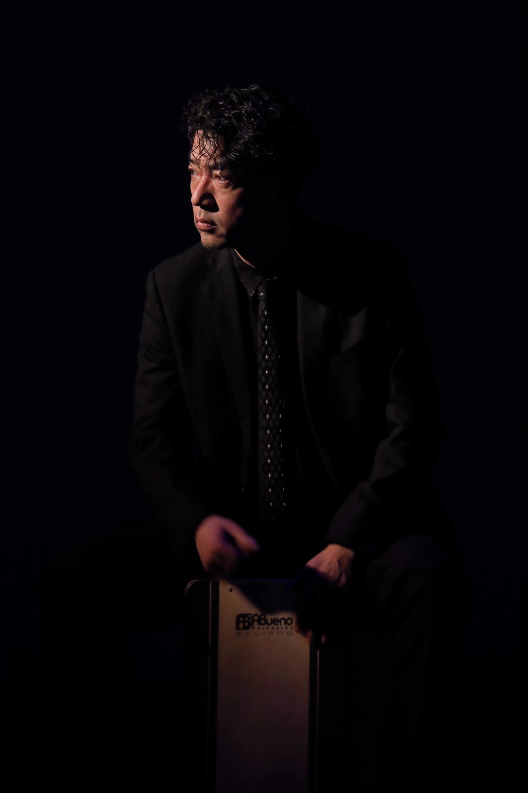 Man in suit sitting in a dark room.