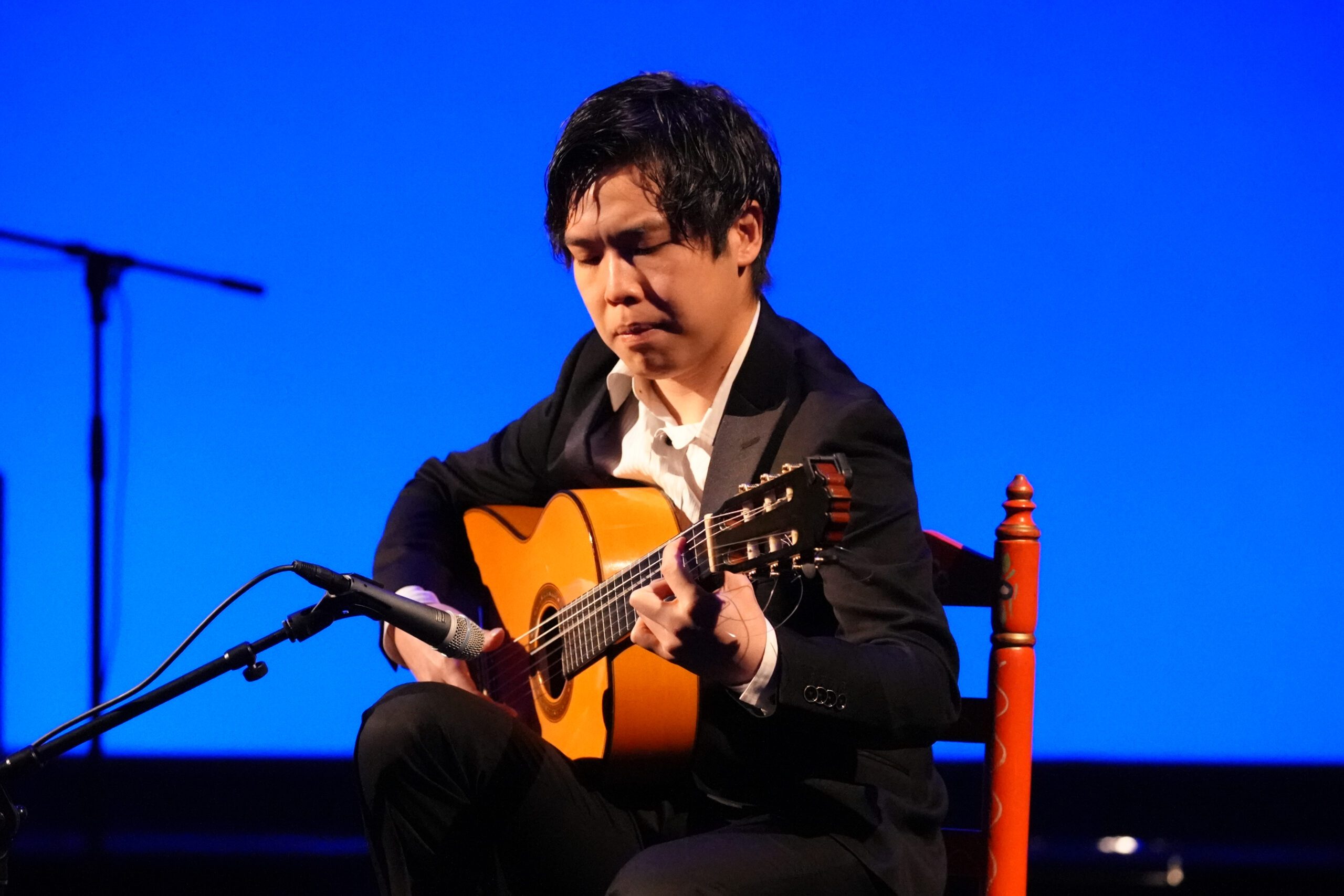 A man in a suit playing an acoustic guitar.