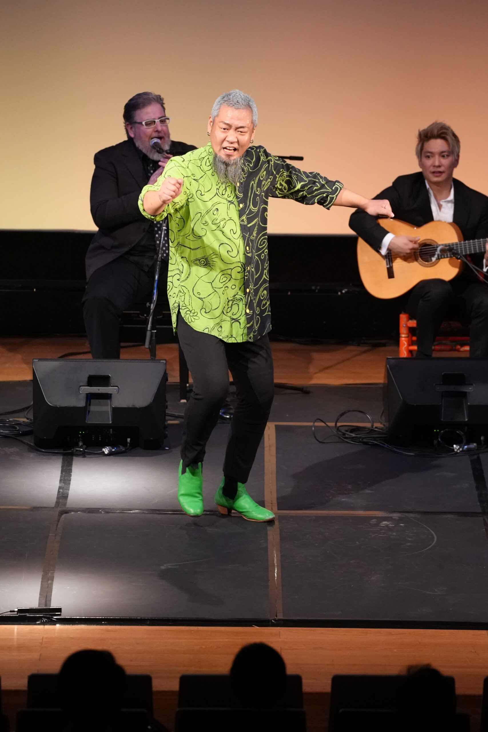 A man on stage with a guitar and a man on stage with a guitar.