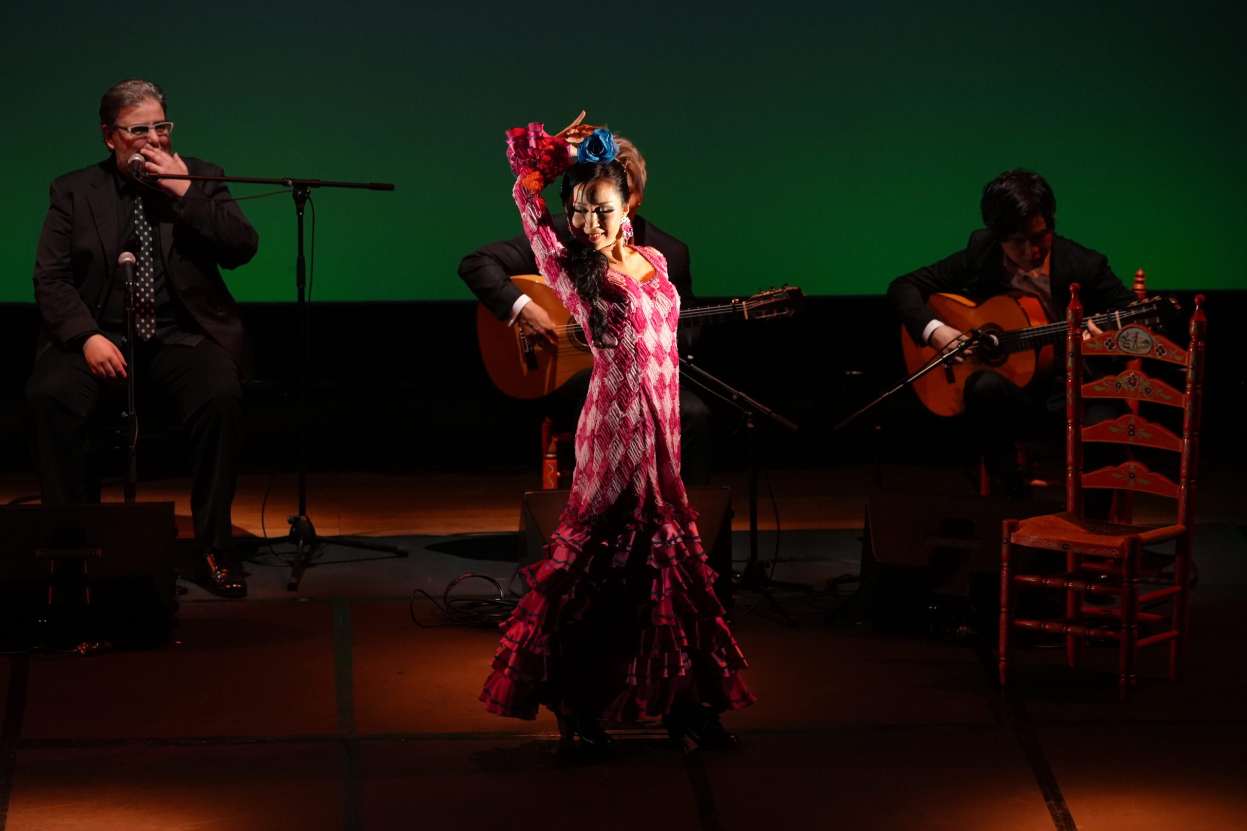 A flamenco dancer performs on stage with a guitar.