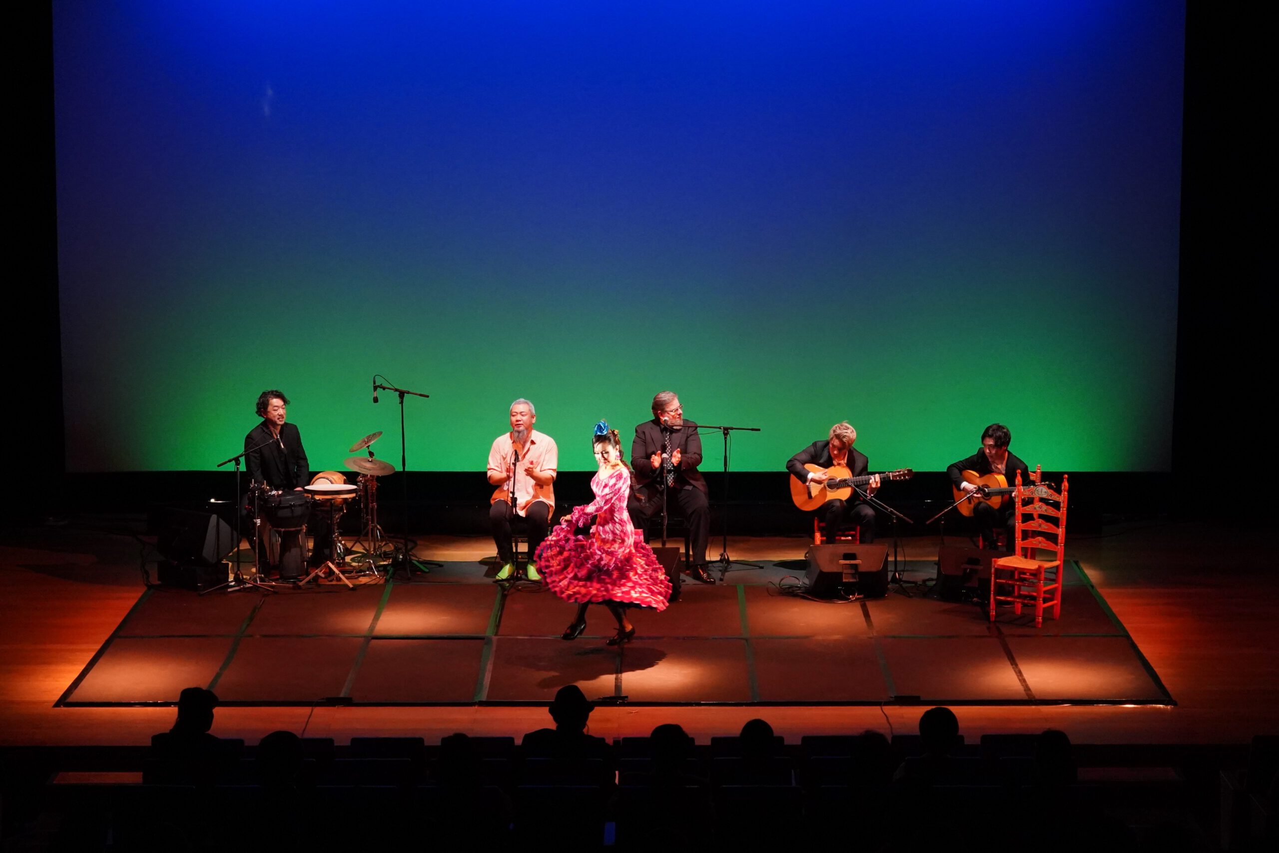 Group of people on stage in front of a green screen.