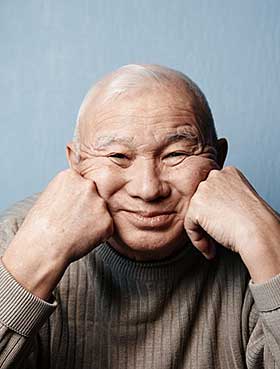 A smiling man with his hand on his chin.