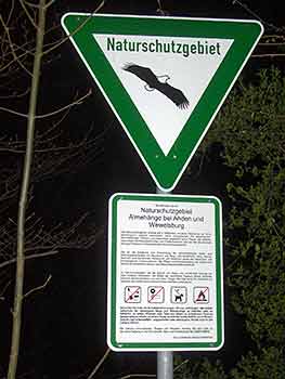 A sign with a flying bird picture and the text "Nature reserve". Below it is a rectangular information sign with detailed text and symbols on the regulations in the nature reserve.