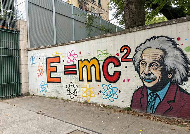 A mural depicts the equation E=mc² next to a portrait of Albert Einstein. Around them are painted various colorful atomic symbols.