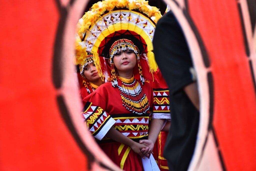 A vibrant duo in traditional attire and ornate headdresses, captured through the Diyandi Festivals red frame.