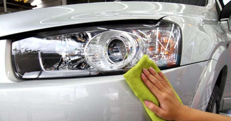 Paglilinis ng isang silver car headlight gamit ang berdeng tela sa Iligan Carwash.