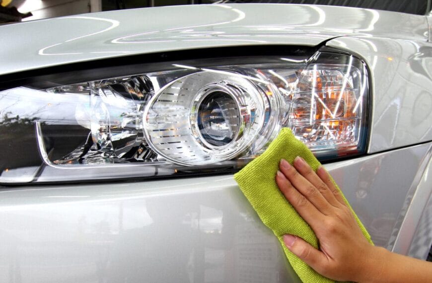 Paglilinis ng isang silver car headlight gamit ang berdeng tela sa Iligan Carwash.