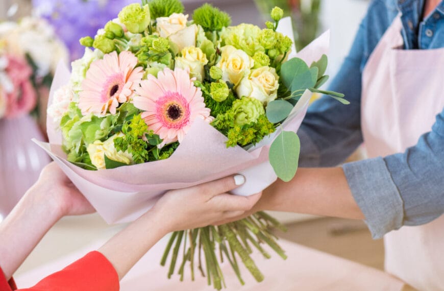 Ang mga kamay ay nagpapalitan ng isang palumpon ng mga rosas na rosas at dilaw na rosas, na nakabalot sa kulay-rosas na papel, na ginawa ng isang tindahan ng bulaklak sa Iligan.