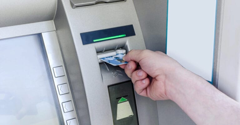 Kamay na nagpasok ng card sa isang Iligan ATM, na may mga pindutan at isang green light indicator sa itaas ng card slot.