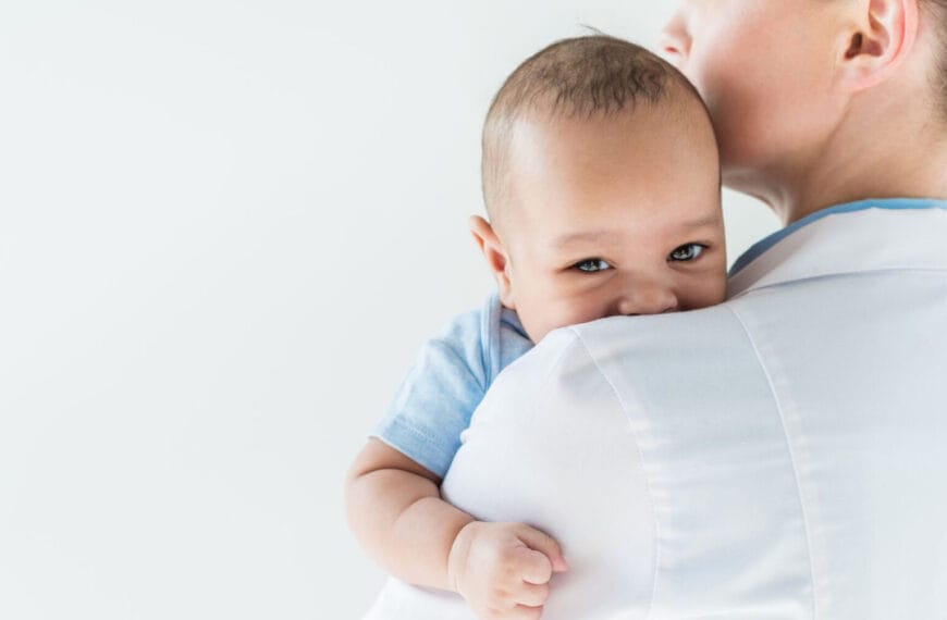 Matanda na may hawak na sanggol sa balikat, sanggol na nakatingin sa kamera, na nagpapaalala sa isang tahimik na sandali sa Pedia Iligan.