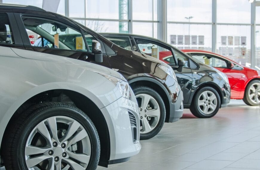 hanay ng apat na rehistradong kotse iligan sa isang maliwanag na showroom, malalaking bintana at gulong na nakasalansan sa background.