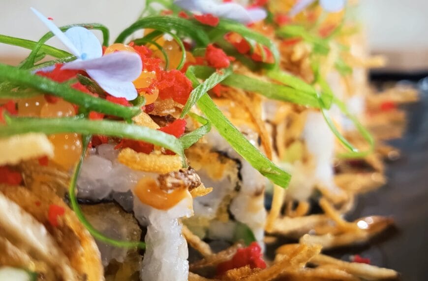 close up ng mga urban cafe signature sushi roll na may isda roe, berdeng sibuyas, at nakakain na bulaklak.