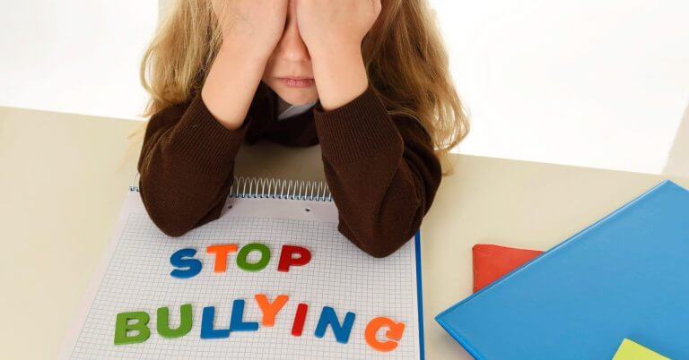 Isang malungkot na bata ang nagtatakip ng mukha sa isang mesa, at binibigyang-diin sa makukulay na titik ang anti bullying ordinance ng Iligan City.