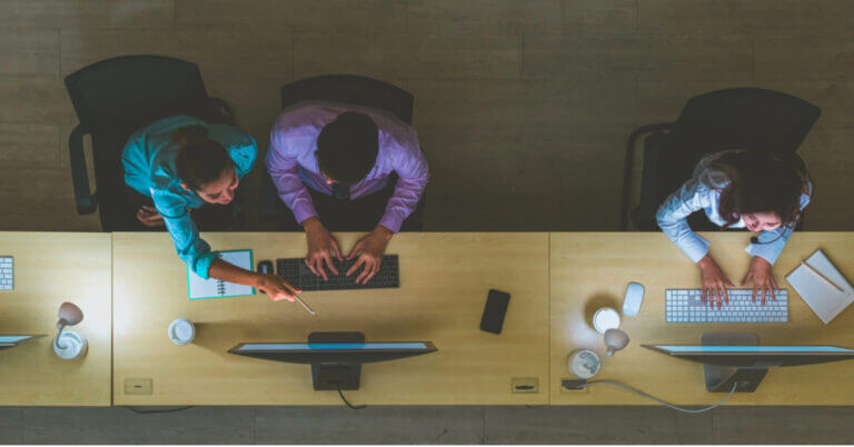 Tatlong tao ang nagtatrabaho sa computer sa isang opisina sa lungsod ng Iligan, dalawa ang nagtutulungan habang ang isa ay nagtatrabaho nang mag-isa, na tiningnan mula sa itaas.