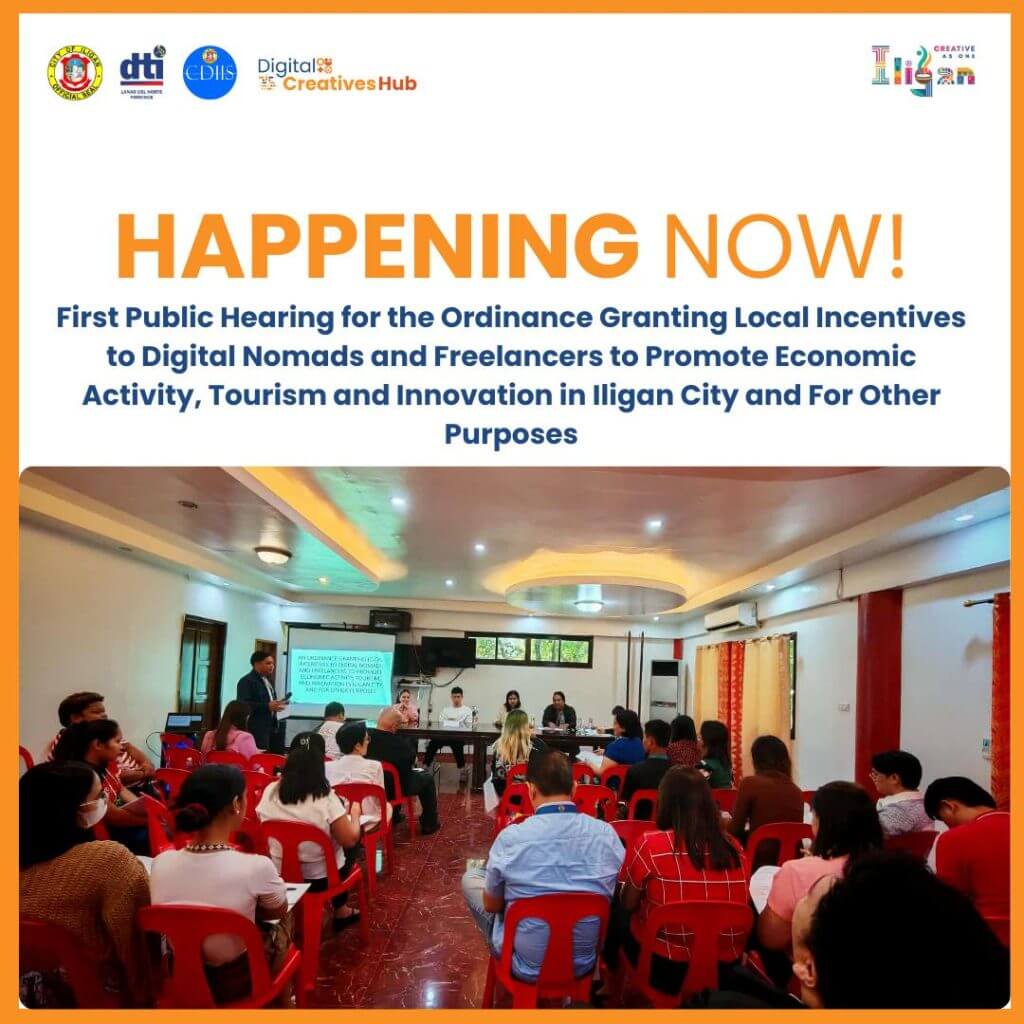 people attend a public hearing in a brightly lit room with a presentation at the front and red chairs.