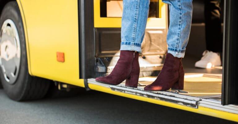 Bumaba ng dilaw na bus ang isang taong naka-roll up na maong at burgundy boots sa isang terminal ng transportasyon sa lungsod ng Iligan.