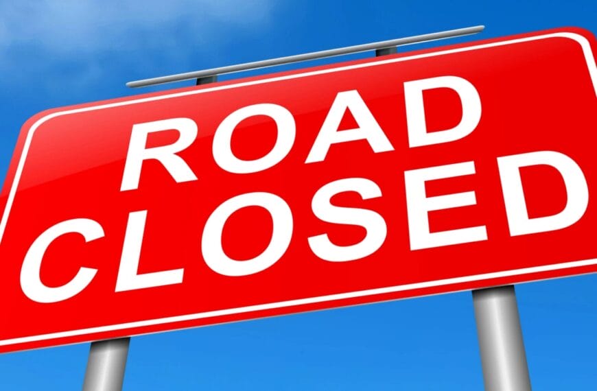 Red Road closed sign na may puting teksto sa Iligan, naka-mount sa dalawang kulay-abo na poste sa ilalim ng asul na kalangitan.