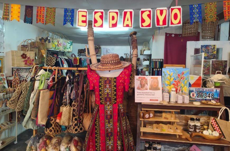 Makukulay na tindahan na may tradisyunal na damit na Pilipino, Iligan arts crafts, bag, sumbrero, painting, at karatula na nagbabasa ng espasyo.