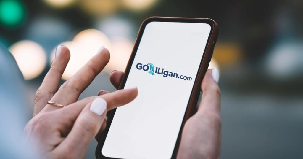 A hand holds a phone displaying the GoLilligan.com logo—discover where to buy SIM cards in Iligan City.