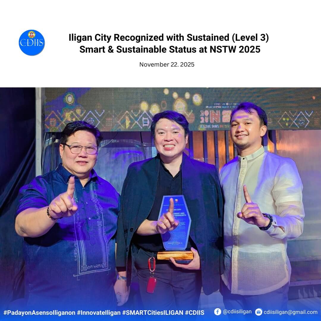 three men smile and hold up one finger; the man in the middle holds a blue and gold award on stage.