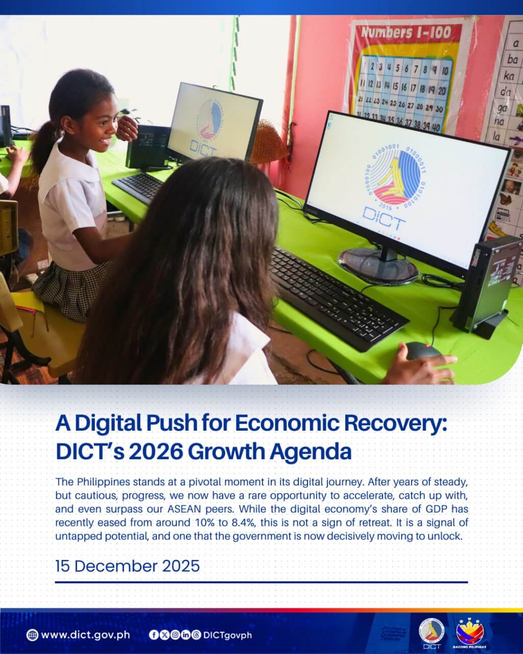 two girls in school uniforms use desktop computers in a classroom with the dict logo on the screens.