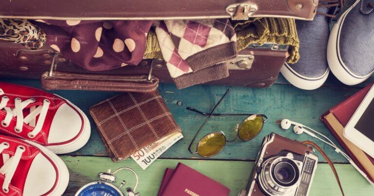 open suitcase with travel essentials on wood, highlighting region 10 tourism and community centered development.