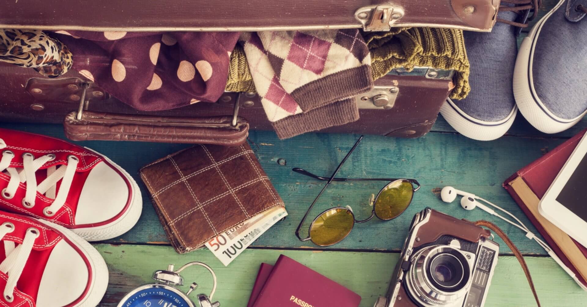 open suitcase with travel essentials on wood, highlighting region 10 tourism and community centered development.