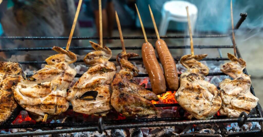 grilled chicken and sausages cooking over hot coals—a must visit spot for foodies in the mindanao travel guide.