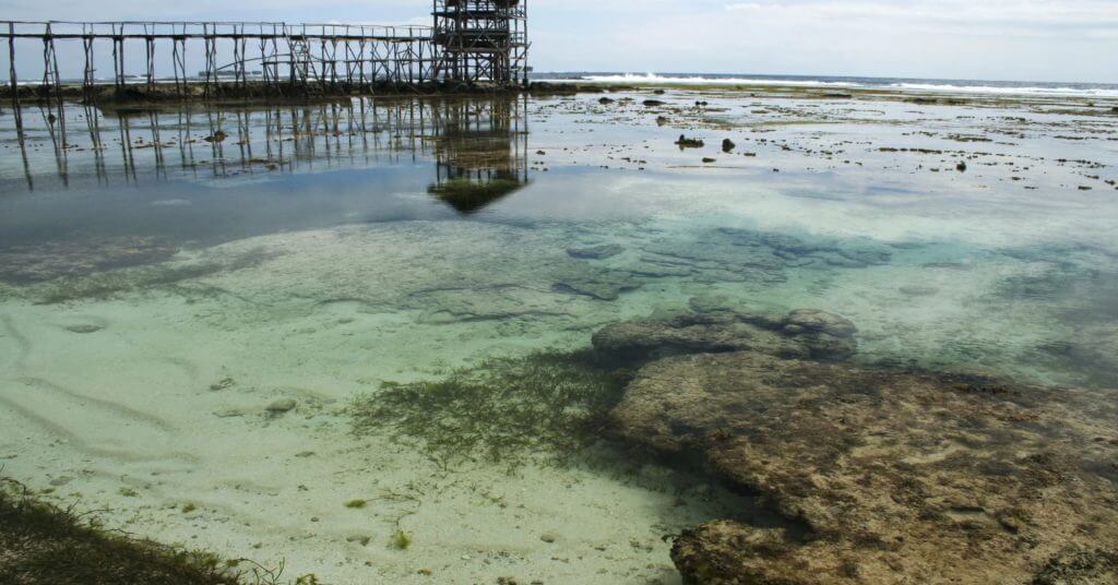 clear shallow tide pool with rocks and seaweed—one of mindanao travel guide’s must visit spots; pier in background.