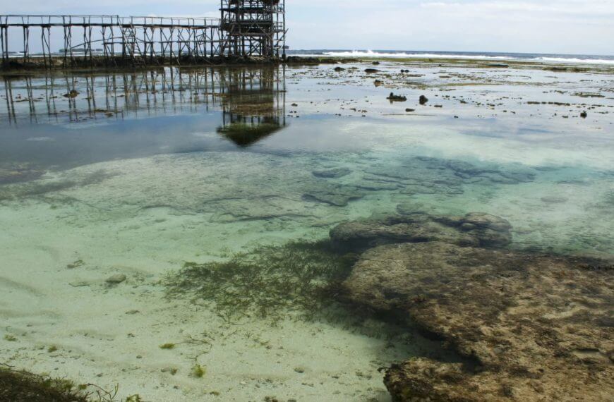 clear shallow tide pool with rocks and seaweed—one of mindanao travel guide’s must visit spots; pier in background.