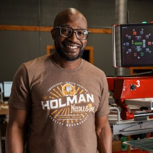 El propietario, Richard Holman, de pie en su taller de bordado y serigrafía en Lawrence, KS