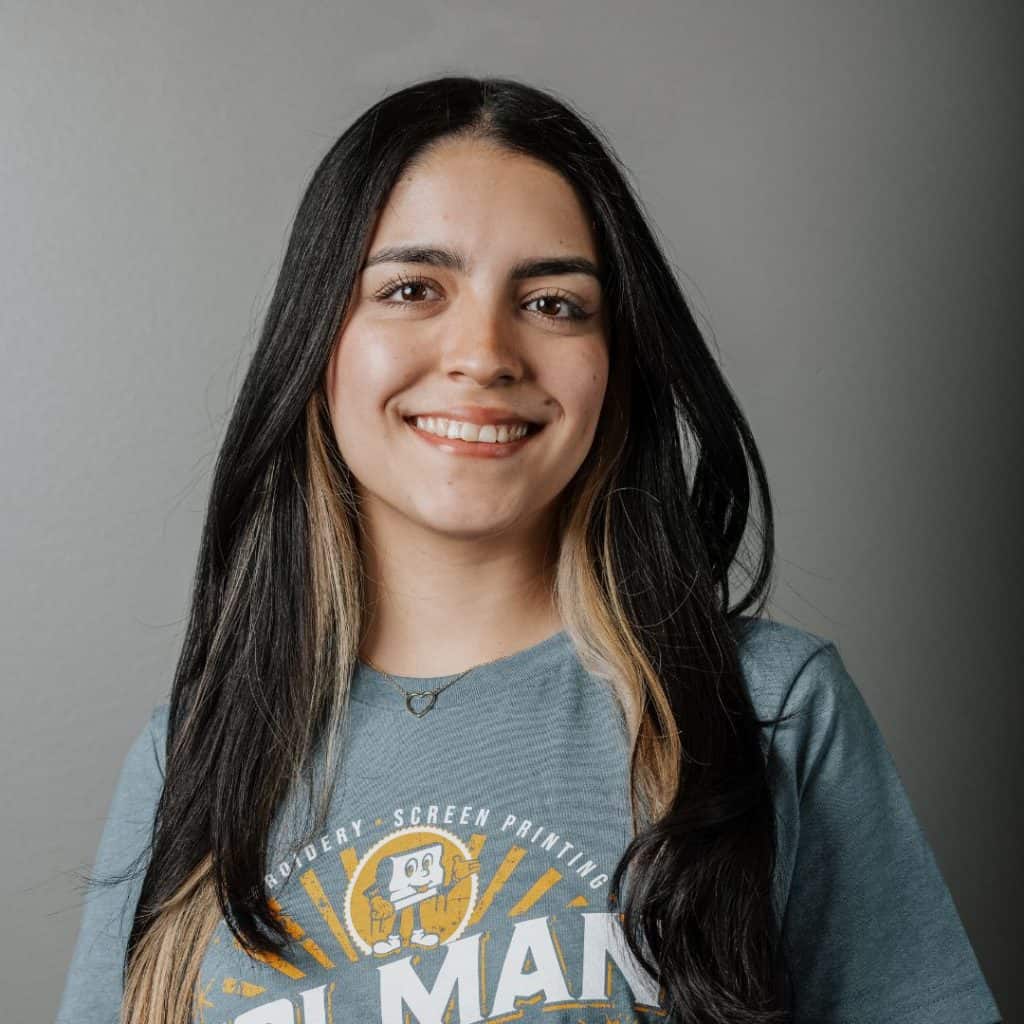 La diseñadora gráfica Ana Mostacero sonriendo con una camiseta personalizada de Holman Needle and Ink.